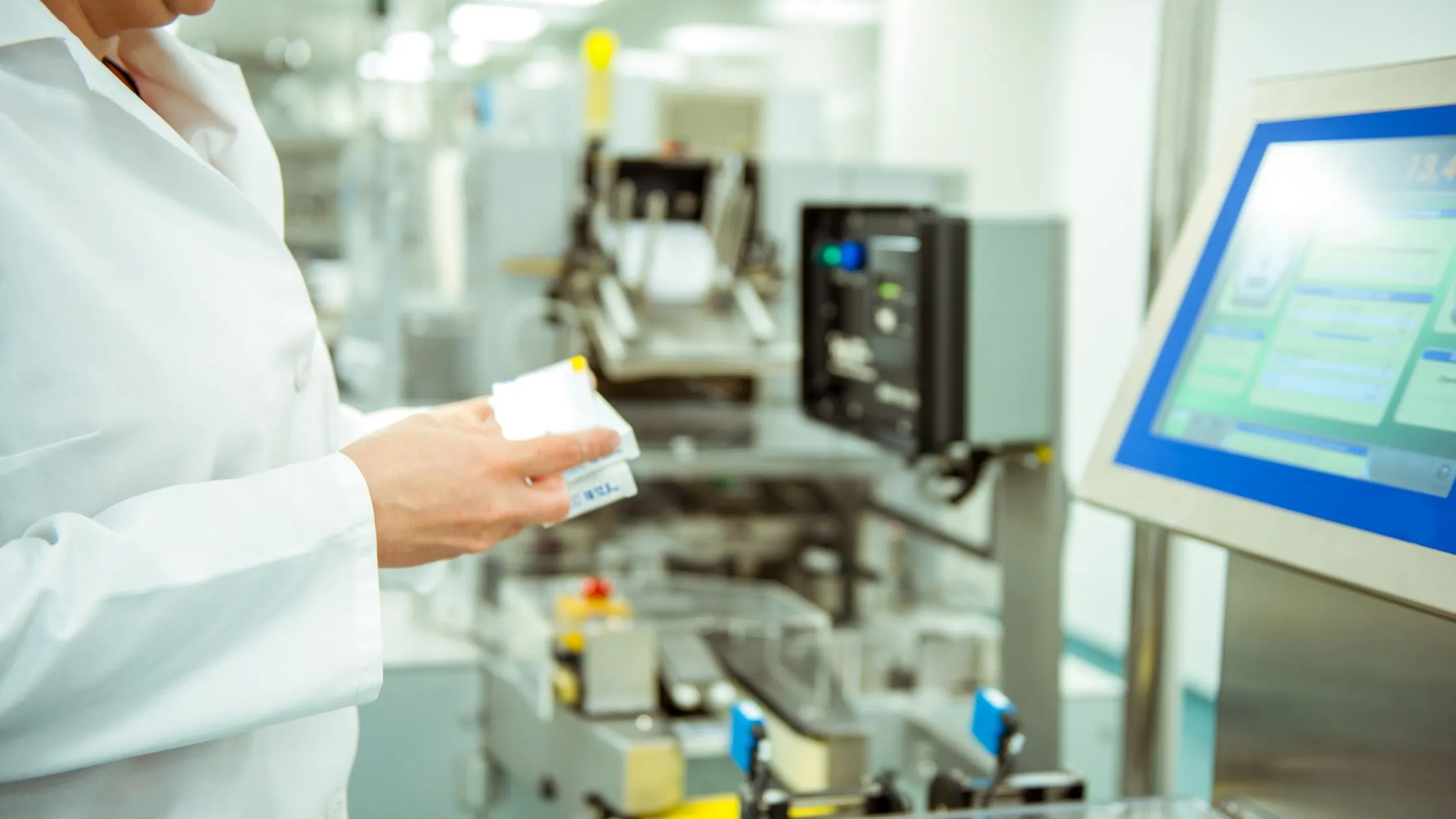 A production specialist checking a printed medicine carton at the packaging line