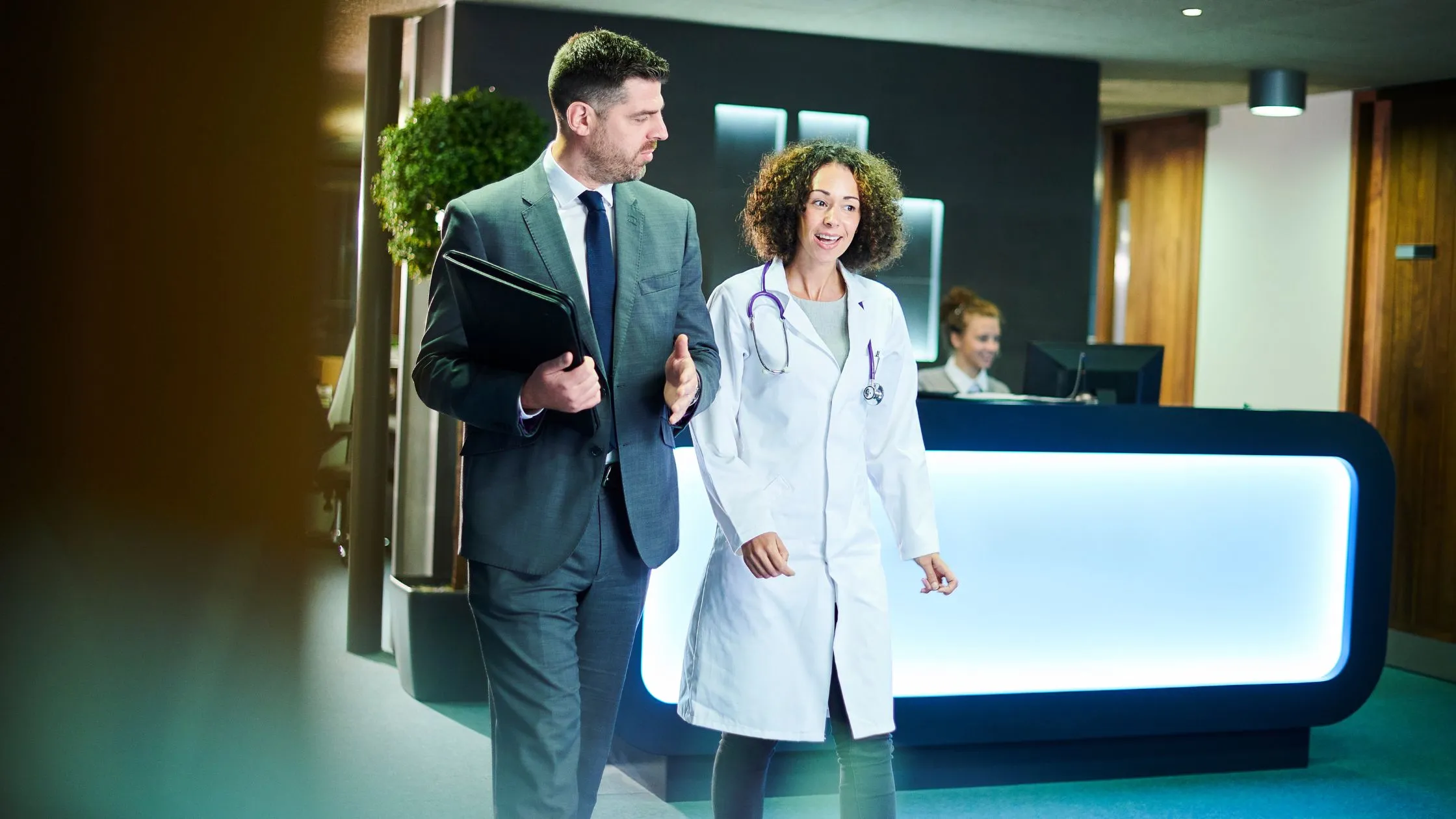 A commercial lead and a healthcare professional walking together through a clinic reception