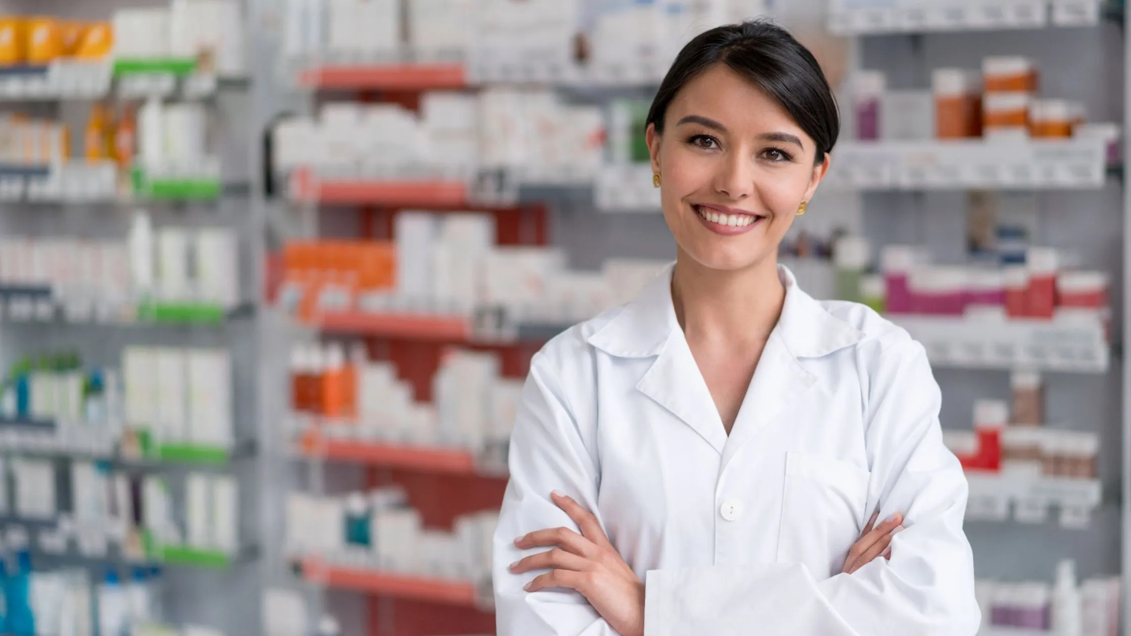A pharmacist standing in front of a fully stocked pharmacy dispensary wall