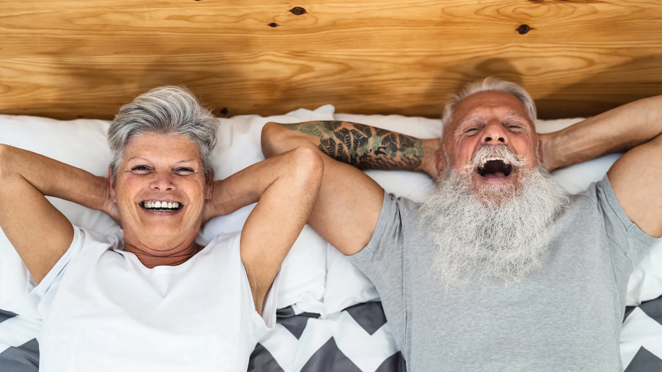 A couple in their sixties laughing together in bed